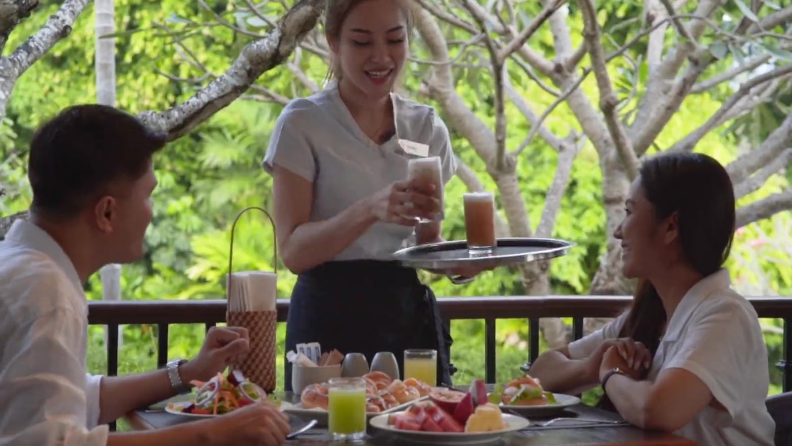 Demonstration frame — terrace breakfast, hands reaching for the tray